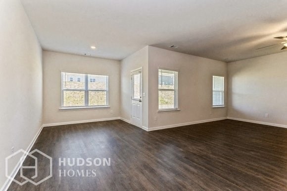 an empty living room with wood flooring and a window