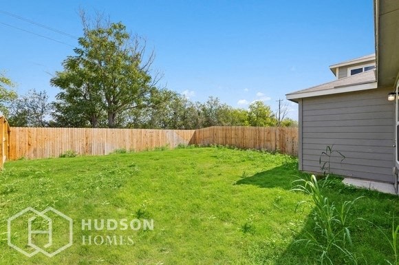a backyard with a fence and a lawn and a house