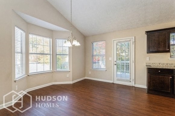 an empty living room with wood floors and a door to a balcony