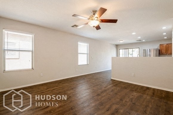 an empty living room with a ceiling fan and a window