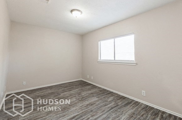 the living room of a home with wood flooring and a window