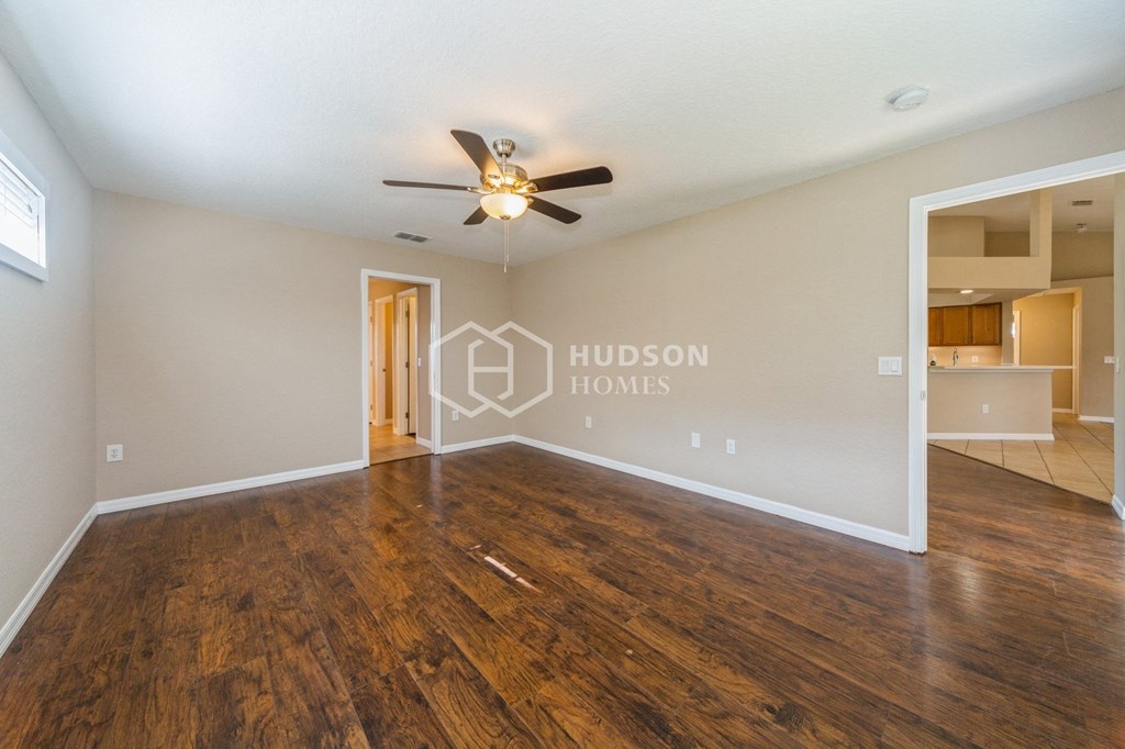 an empty living room with wood floors and a ceiling fan