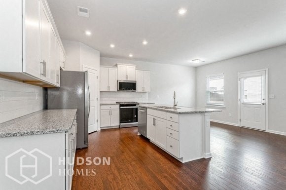 a large kitchen with white cabinets and a stainless steel refrigerator