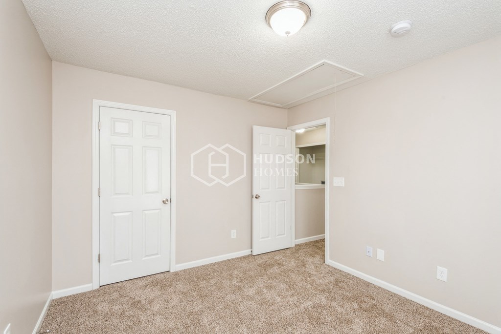 a bedroom with white doors and carpeted flooring and a closet