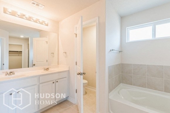 a white bathroom with a tub and a sink and a mirror