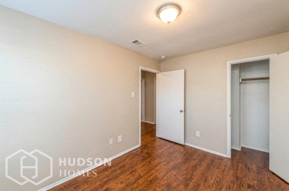 a bedroom with wood flooring and a door to a closet