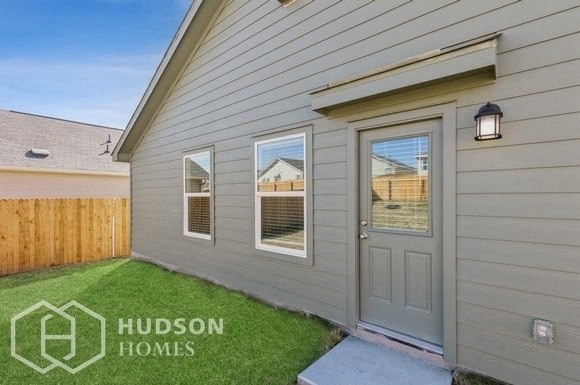 the backyard of a home with a blue door and green grass