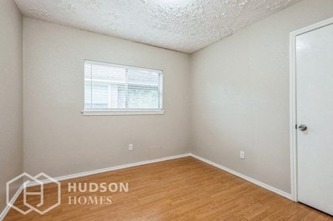 a bedroom with a wood floor and a window