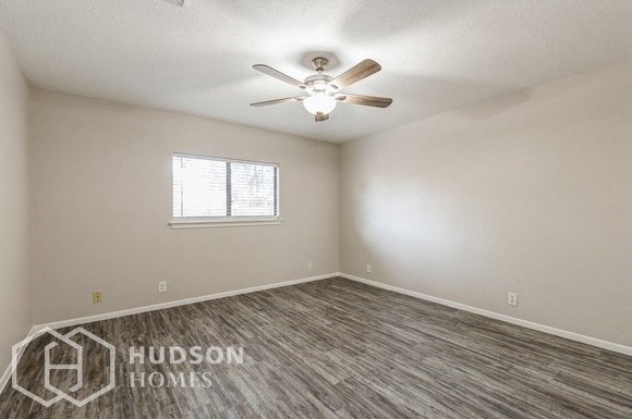 an empty bedroom with a ceiling fan and a window