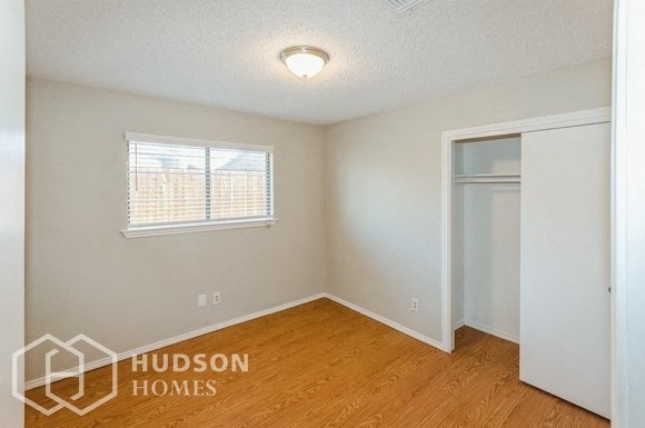 a bedroom with a closet and a window and a wooden floor