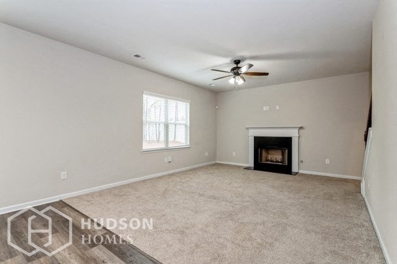 an empty living room with a fireplace and a ceiling fan