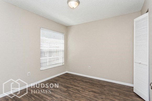 the living room of a home with a large window and wood flooring