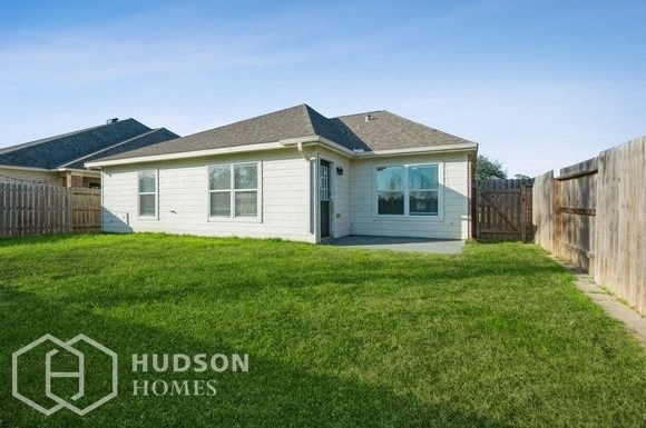 a small white house in a fenced in backyard with a lawn