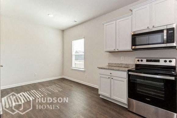 a kitchen with white cabinets and a stove and a microwave