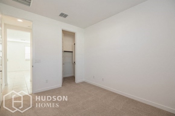 a bedroom with white walls and a door to a closet