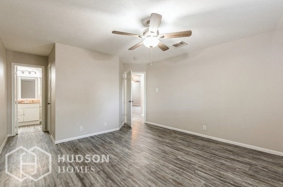 an empty living room with a ceiling fan and a bathroom