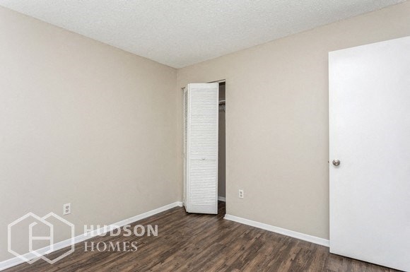 the spacious living room with wood flooring and white walls