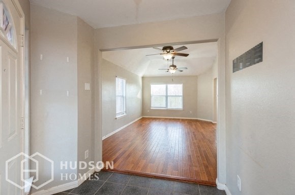 an empty living room with wood floors and a ceiling fan
