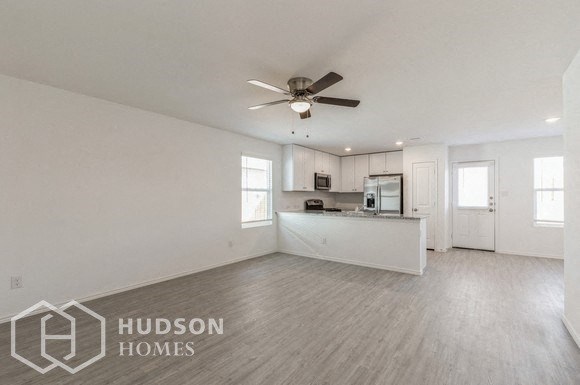 an empty living room and kitchen with a ceiling fan