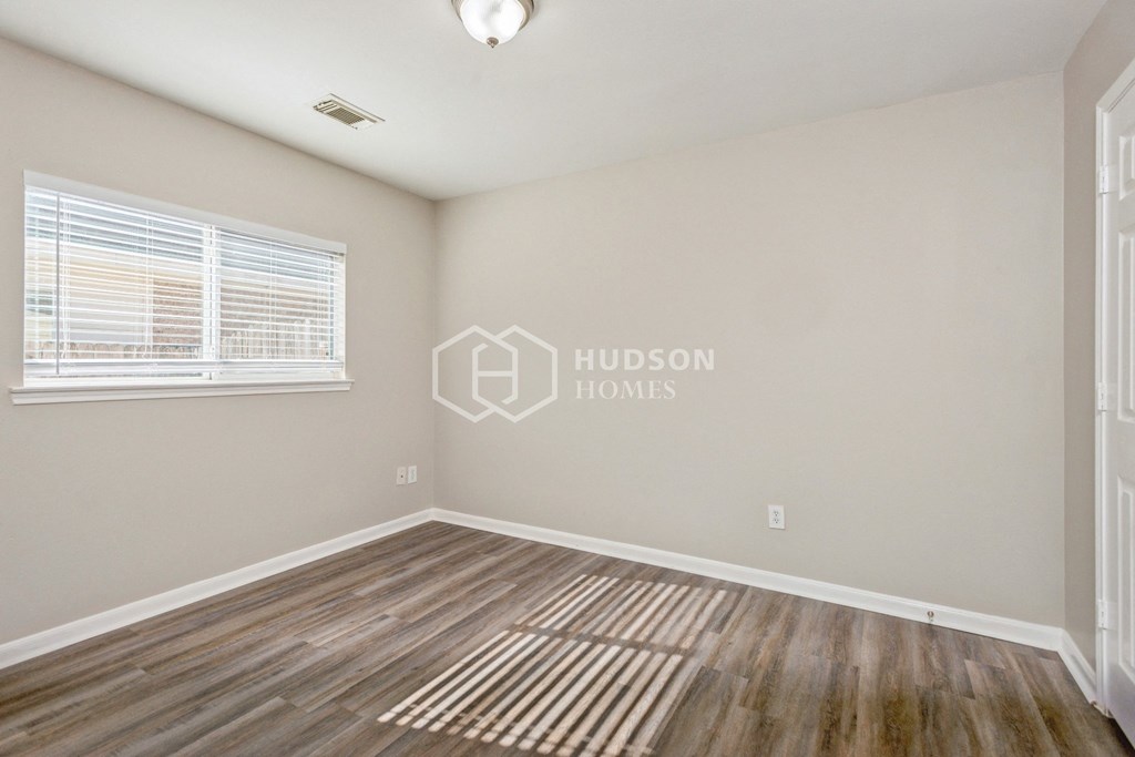 a bedroom with a hardwood floor and a window