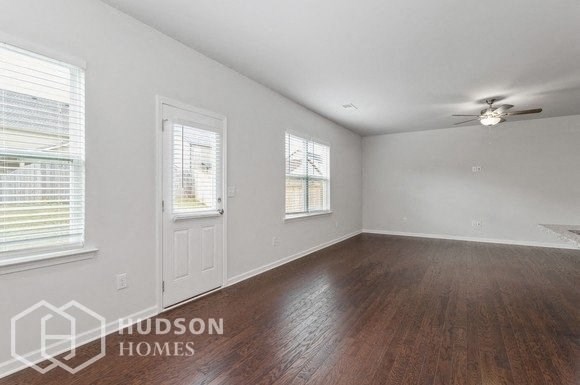 an empty living room with wood floors and a ceiling fan