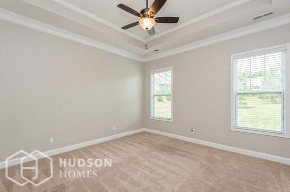 an empty living room with a ceiling fan and two windows