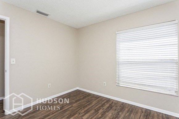 a bedroom with a large window and wooden flooring and a window