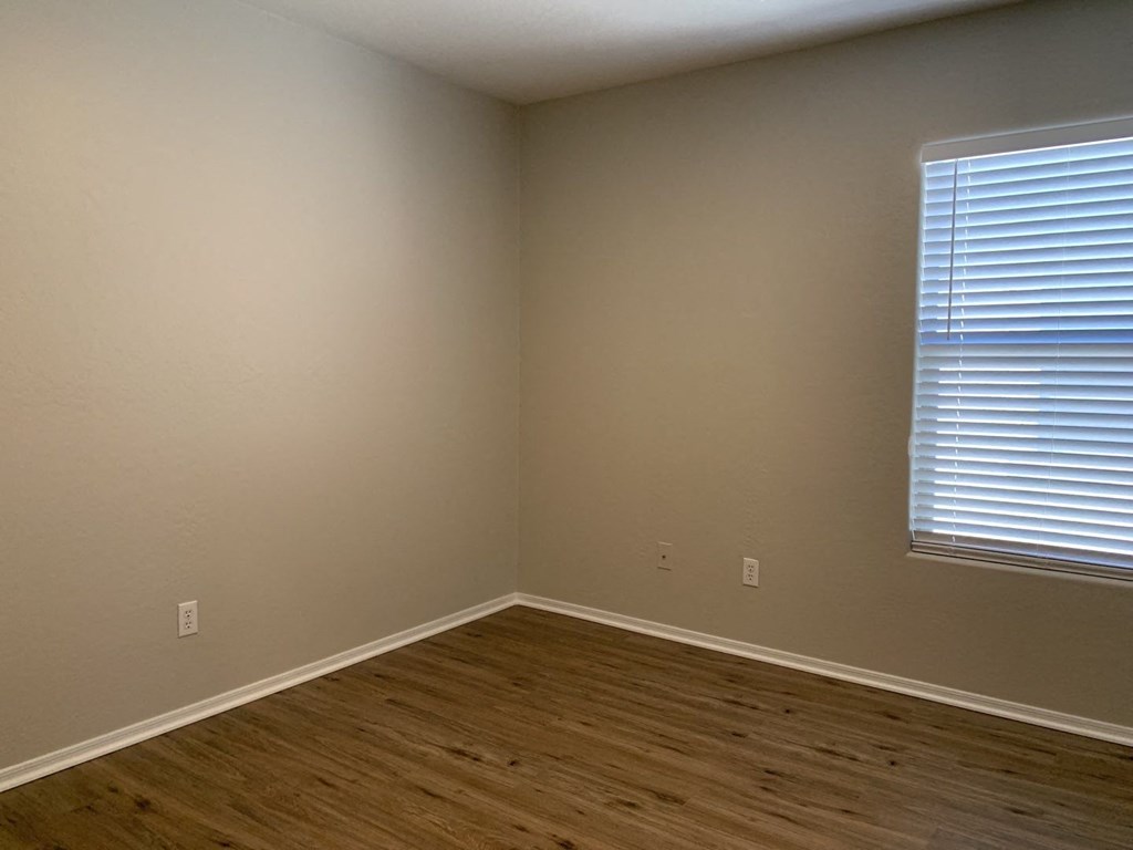 an empty room with a window and wooden floors