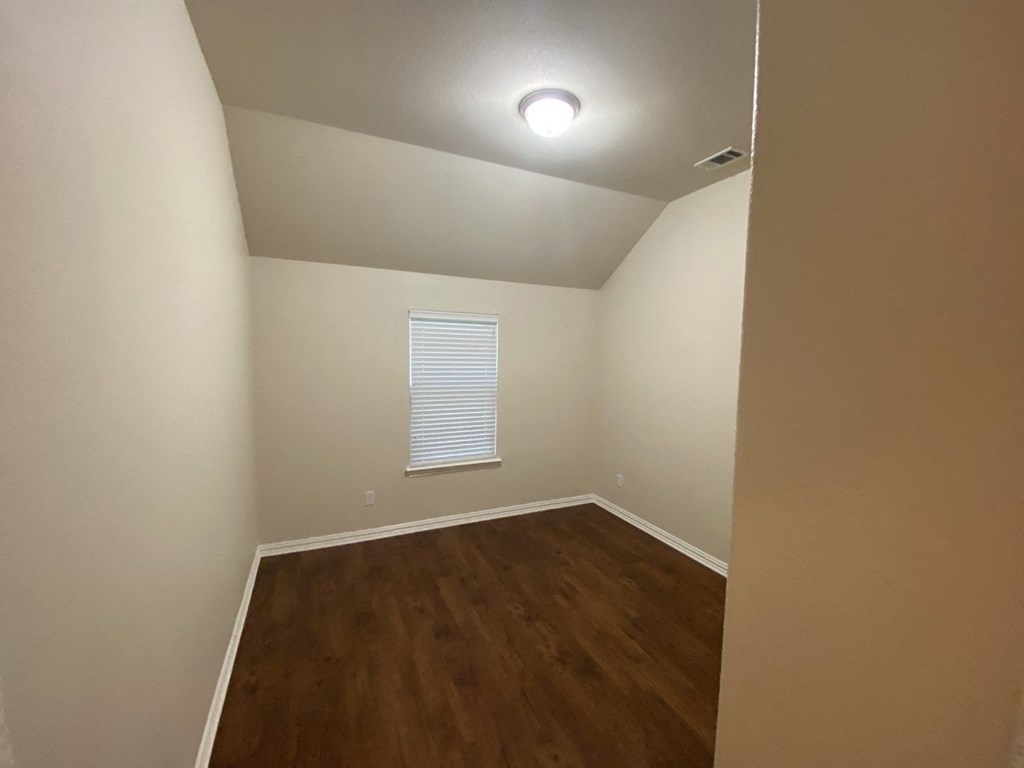 an empty room with wooden floors and a window