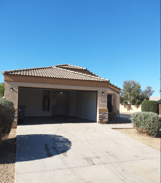 a garage with a roof and a driveway in front of a house
