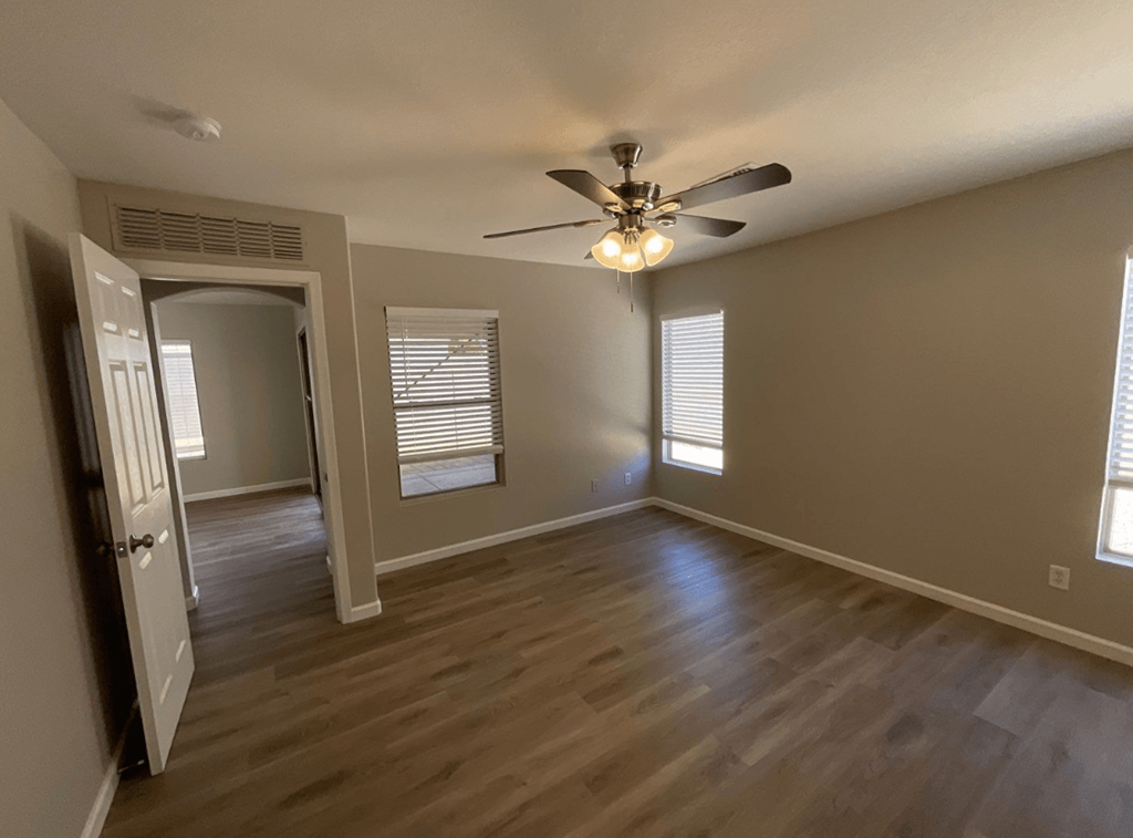 an empty living room with wood floors and a ceiling fan