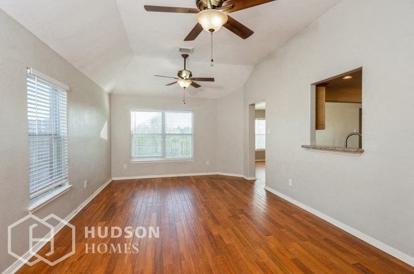 an empty living room with wood flooring and a ceiling fan