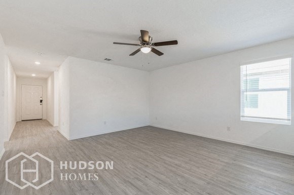 an empty living room with a ceiling fan and white walls