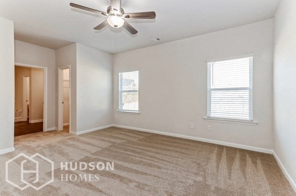 an empty living room with a ceiling fan and two windows