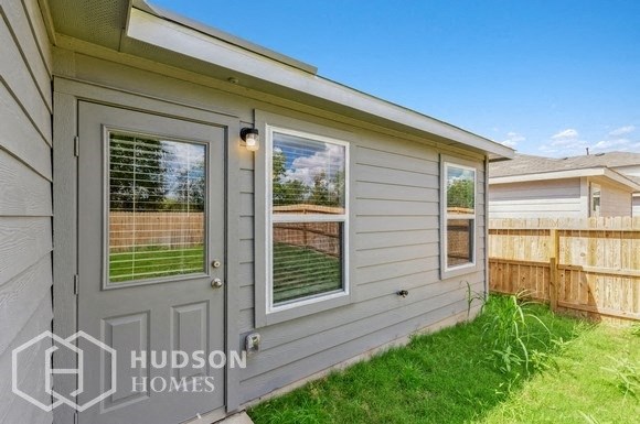 the side of a house with a backdoor and a lawn