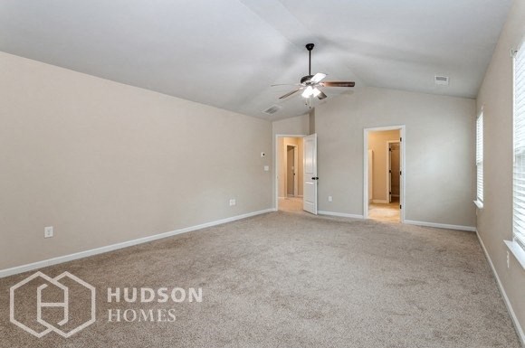 an empty living room with a ceiling fan and a door to a hallway