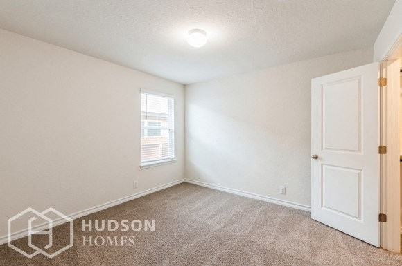 the living room of a home with white walls and a window