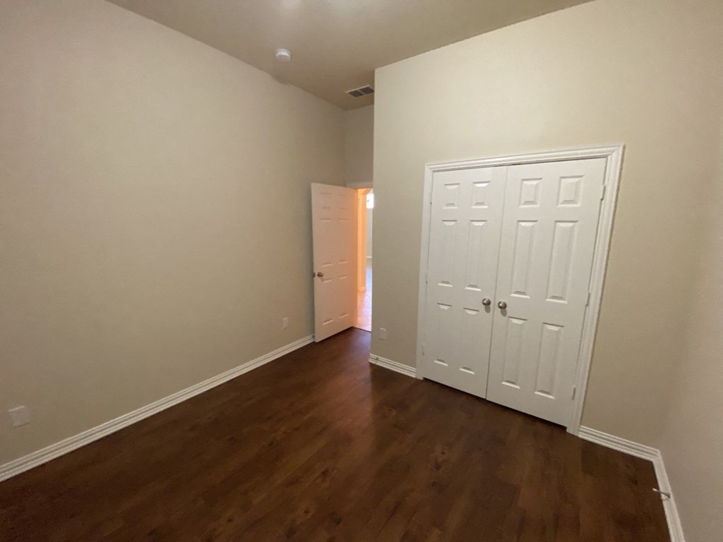 a bedroom with a door to a closet and a hard wood floor