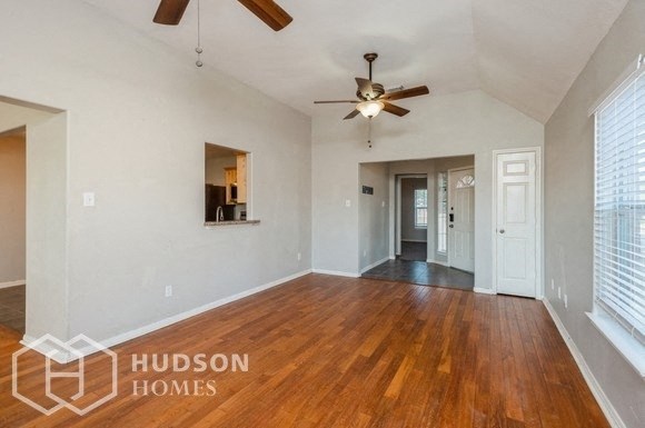 an empty living room with wood floors and a ceiling fan