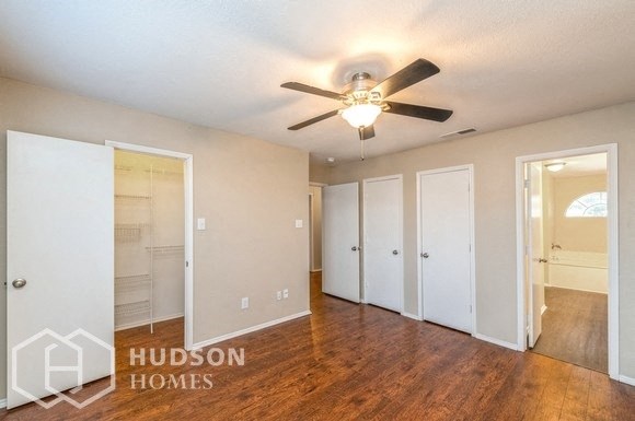 an empty living room with a ceiling fan and a closet