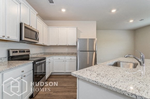 a kitchen with white cabinets and granite counter tops and stainless steel appliances