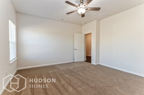 an empty living room with a ceiling fan and white walls