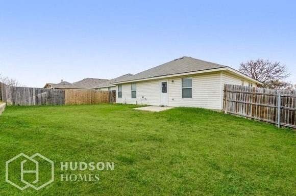 a backyard with a small white house and a fence