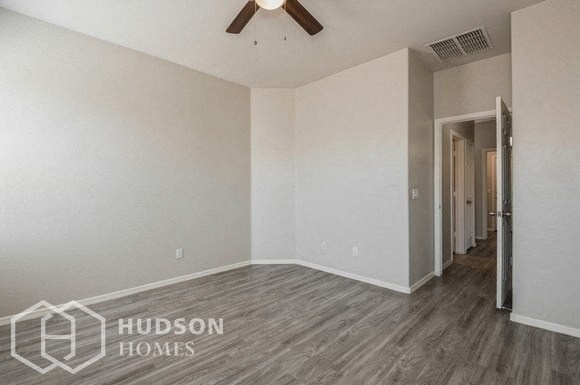 an empty living room with a ceiling fan and wood floors
