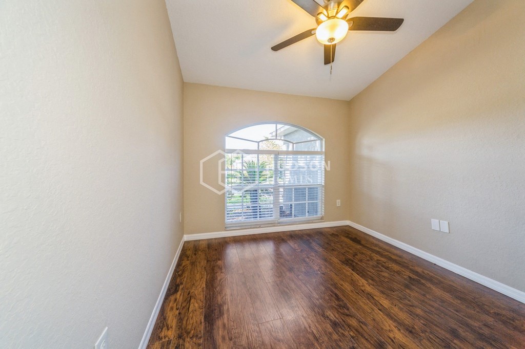 an empty living room with a large window and a ceiling fan