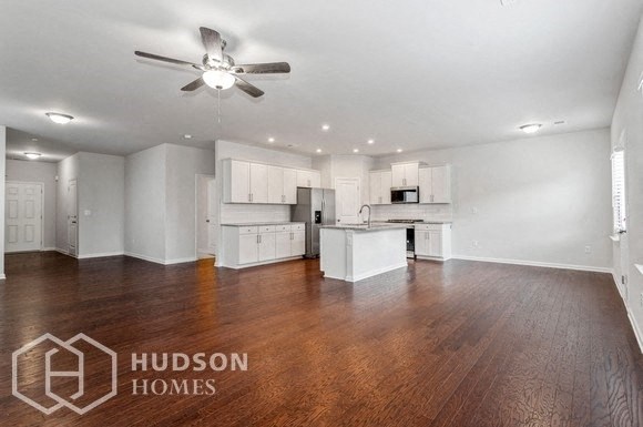 an empty living room and kitchen with a ceiling fan
