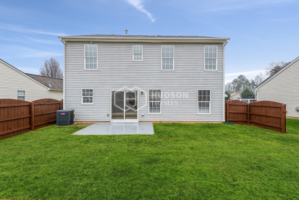a backyard with a white house with a patio and a wooden fence