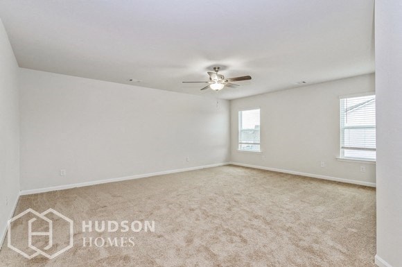 an empty living room with a ceiling fan and a window