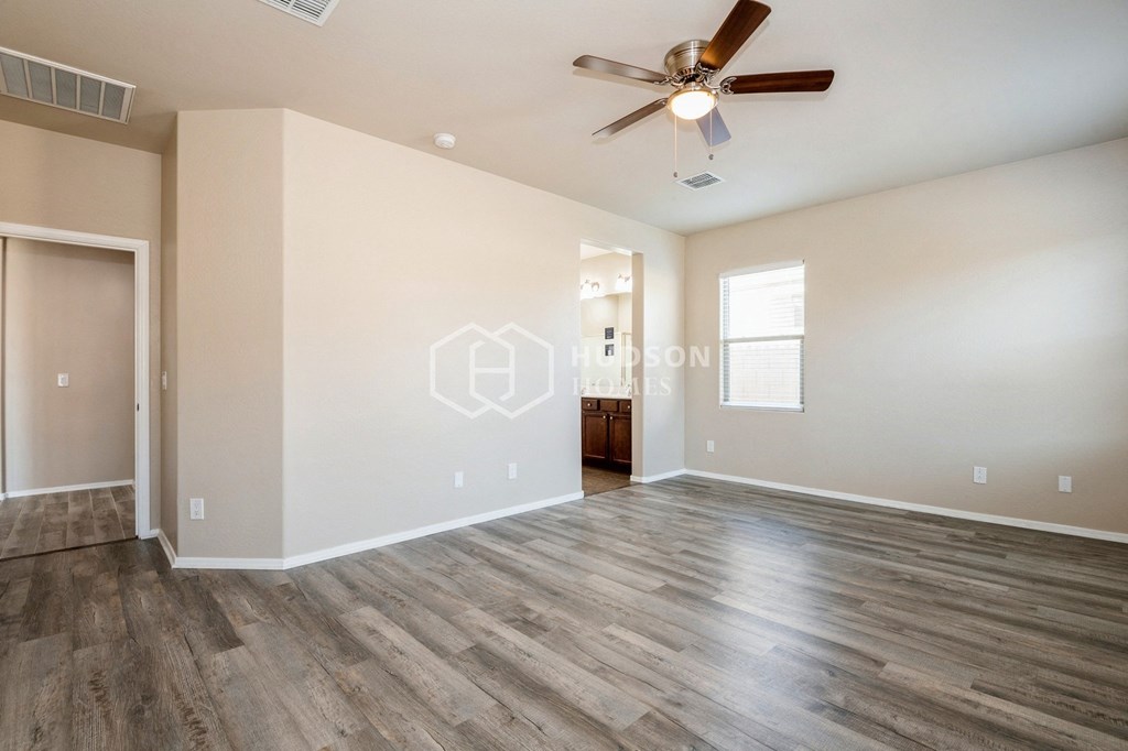 the spacious living room with hardwood floors and a ceiling fan