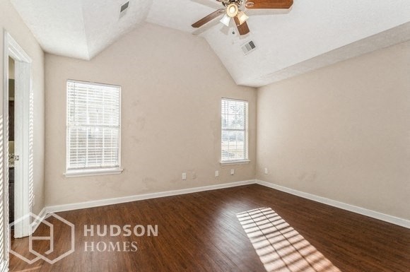 an empty living room with wood floors and a ceiling fan